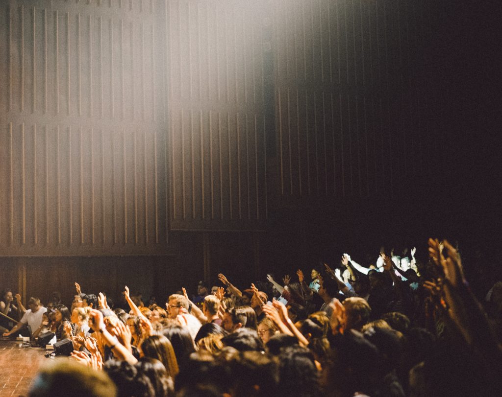 students raising their hands in a full lecture hall