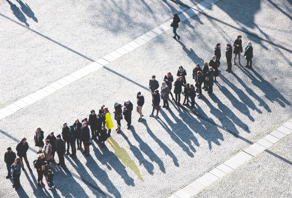 people standing in line on a paved lot